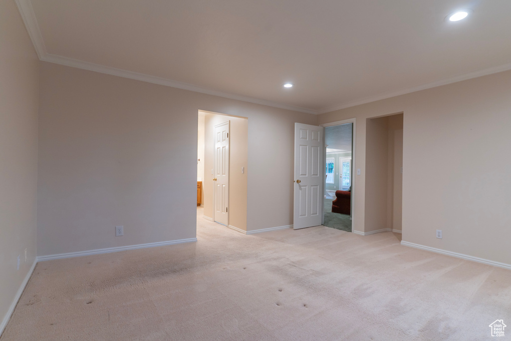 Empty room featuring ornamental molding, baseboards, recessed lighting, and light carpet