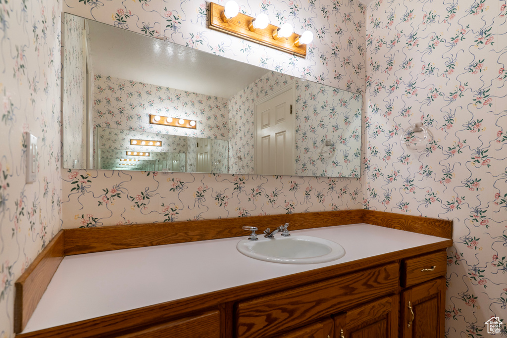 Bathroom featuring wallpapered walls and vanity