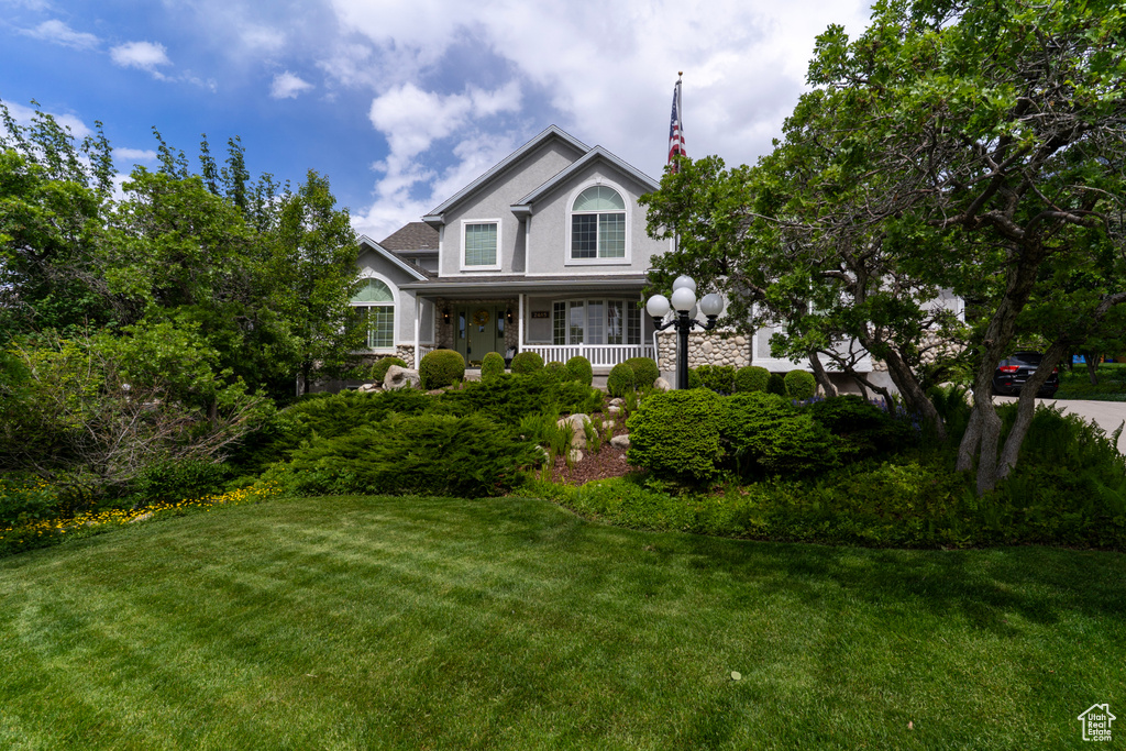 View of front facade with a front yard, a porch, and stucco siding