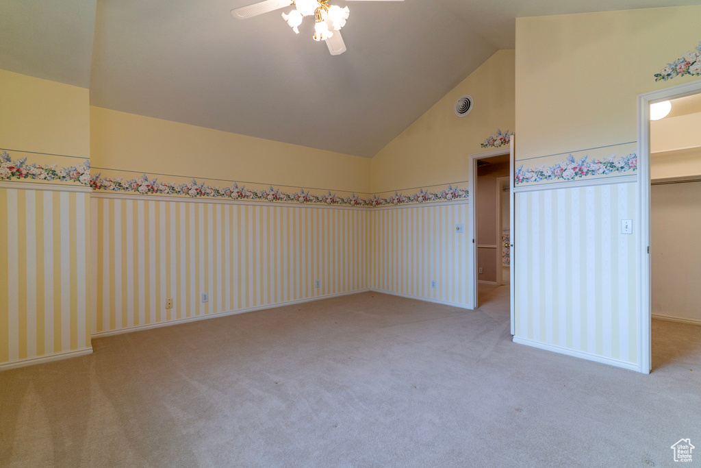 Unfurnished bedroom featuring a walk in closet, carpet, high vaulted ceiling, a ceiling fan, and a closet