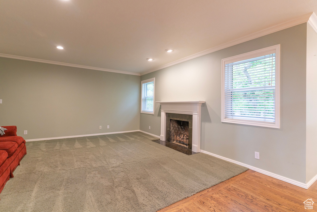 Unfurnished living room with a fireplace with flush hearth, baseboards, crown molding, recessed lighting, and wood finished floors