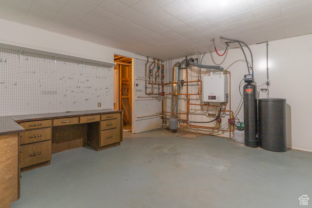 Below grade area featuring a workshop area, tankless water heater, and a water softener