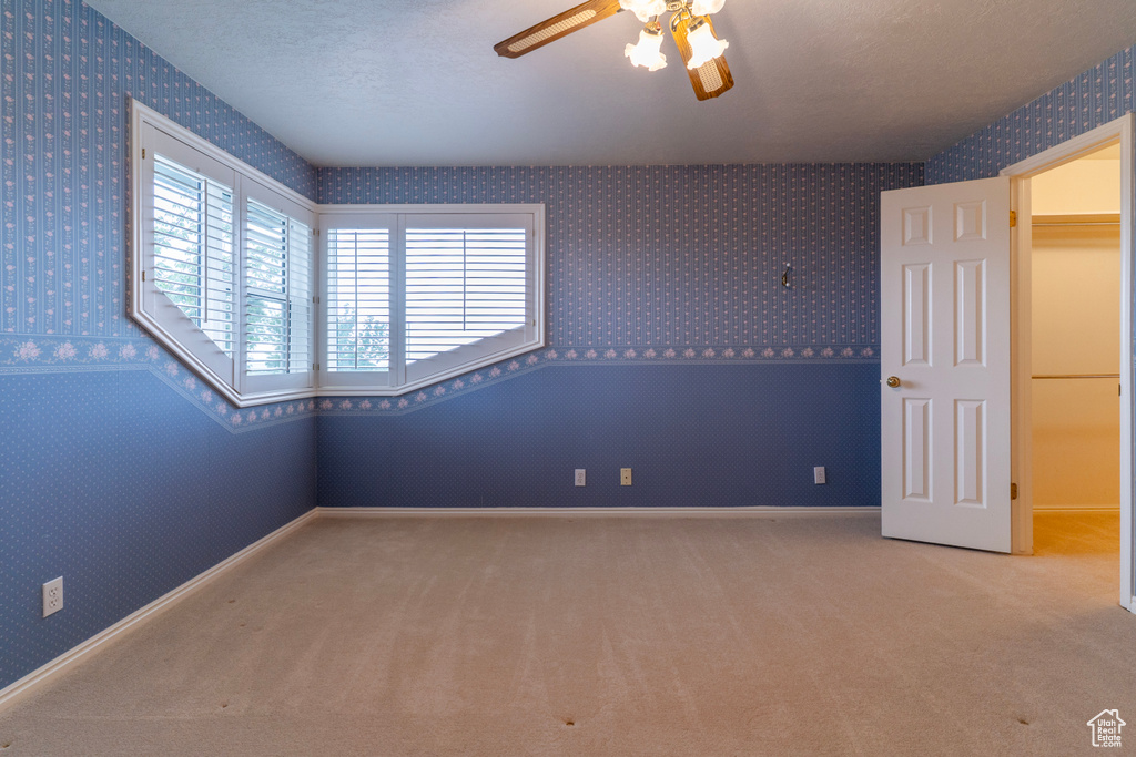 Unfurnished room featuring wallpapered walls, a ceiling fan, carpet, and baseboards