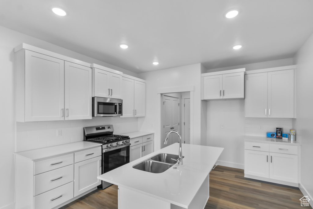 Kitchen featuring appliances with stainless steel finishes, a sink, white cabinetry, an island with sink, and recessed lighting