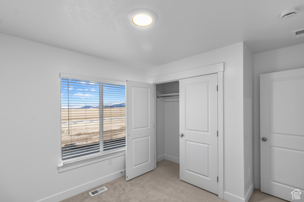 Unfurnished bedroom featuring light carpet, baseboards, and a closet