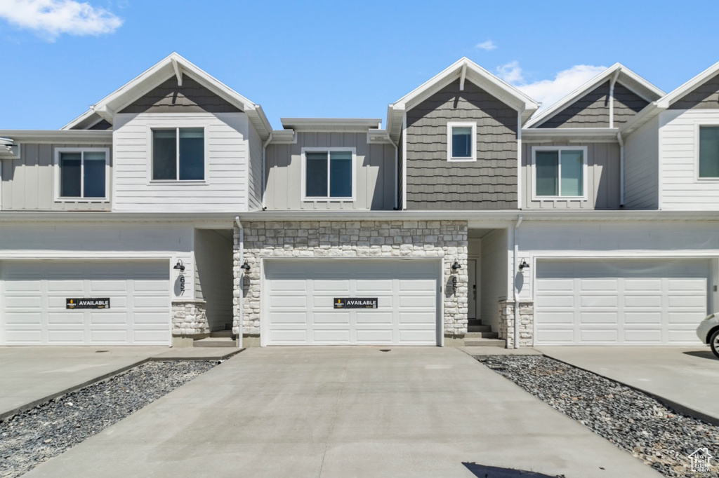 View of front of house featuring board and batten siding, a garage, stone siding, and concrete driveway
