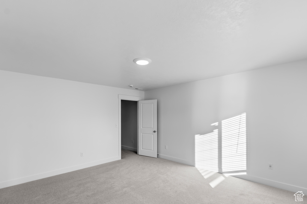 Unfurnished room featuring light carpet and baseboards