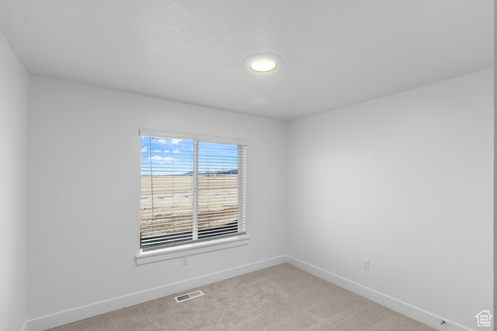 Empty room featuring baseboards and light carpet
