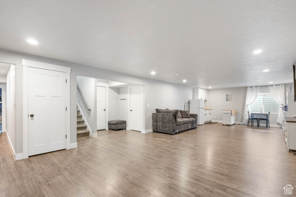 Living room with recessed lighting, wood finished floors, stairs, and baseboards