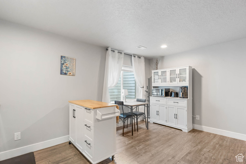 Office area featuring baseboards, light wood-style flooring, a textured ceiling, and recessed lighting