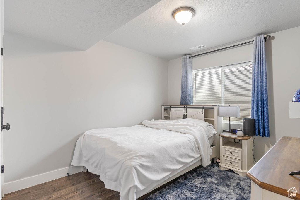 Bedroom with baseboards, dark wood-style floors, and a textured ceiling