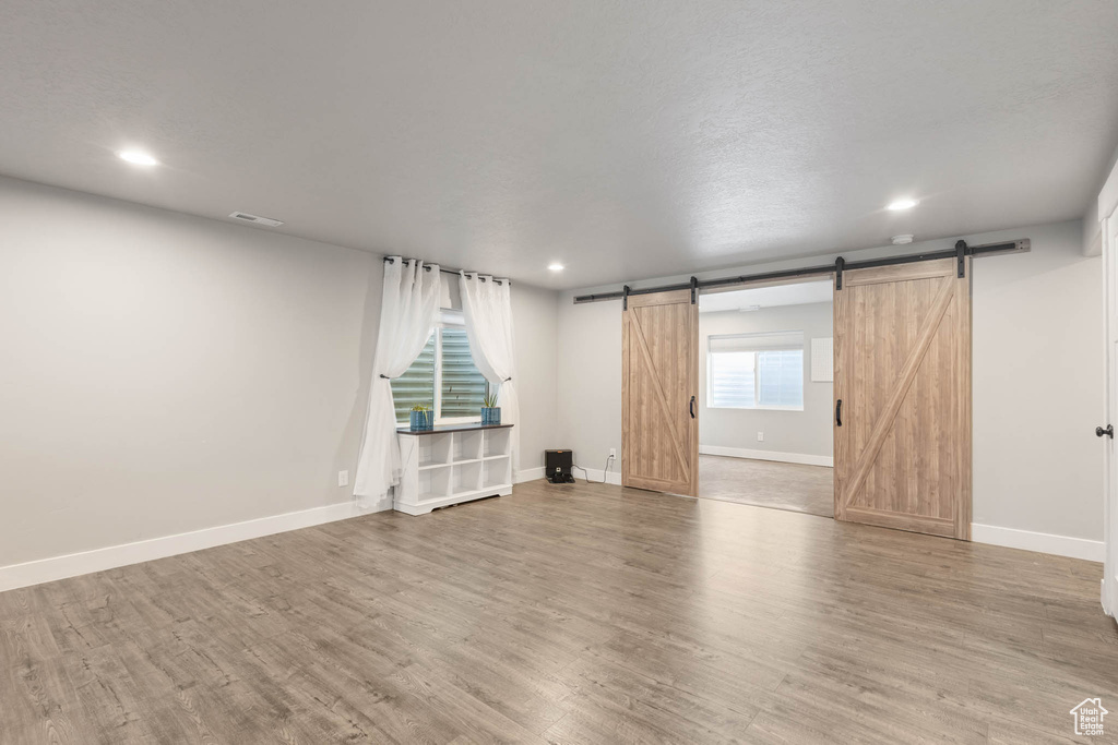 Spare room featuring a barn door, wood finished floors, baseboards, and recessed lighting