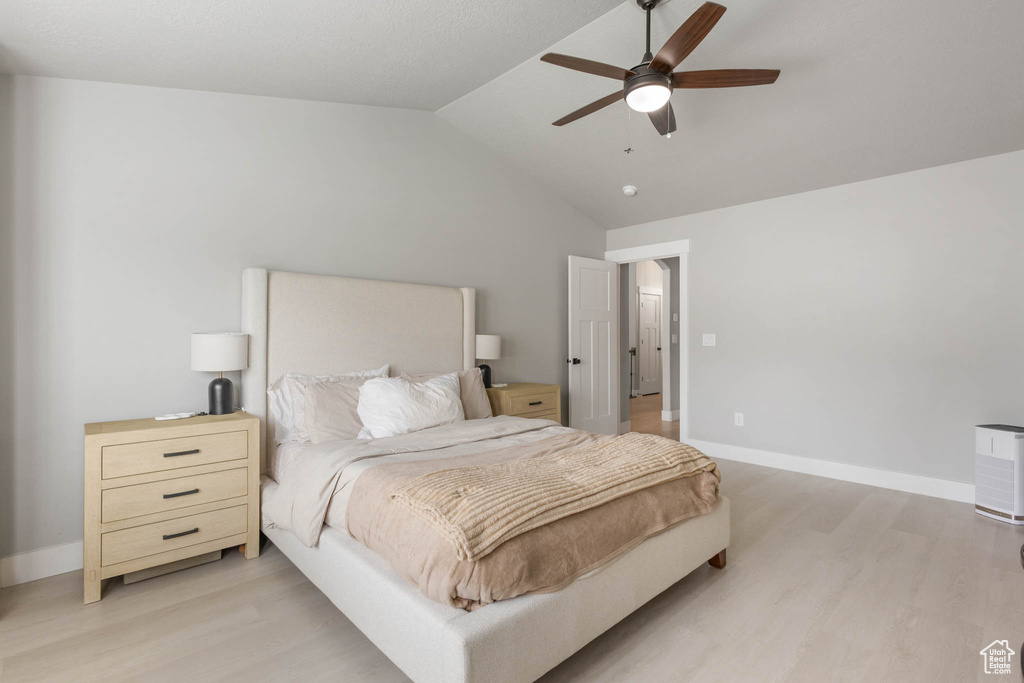 Bedroom featuring light wood-style floors, lofted ceiling, baseboards, and ceiling fan
