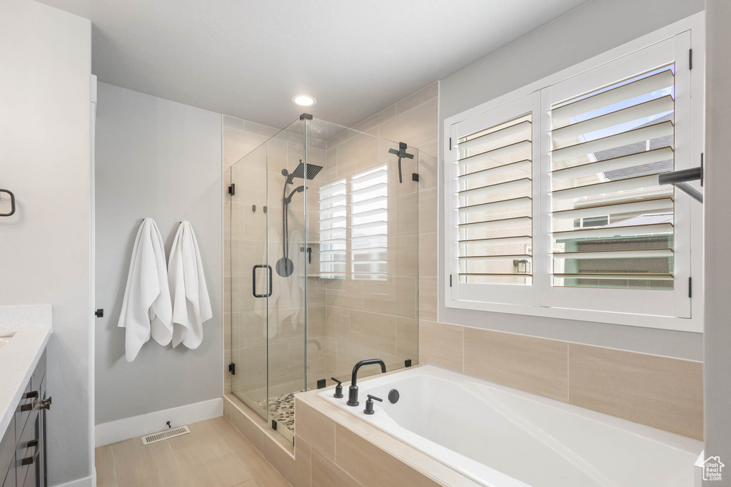 Bathroom featuring a stall shower, a bath, vanity, and baseboards