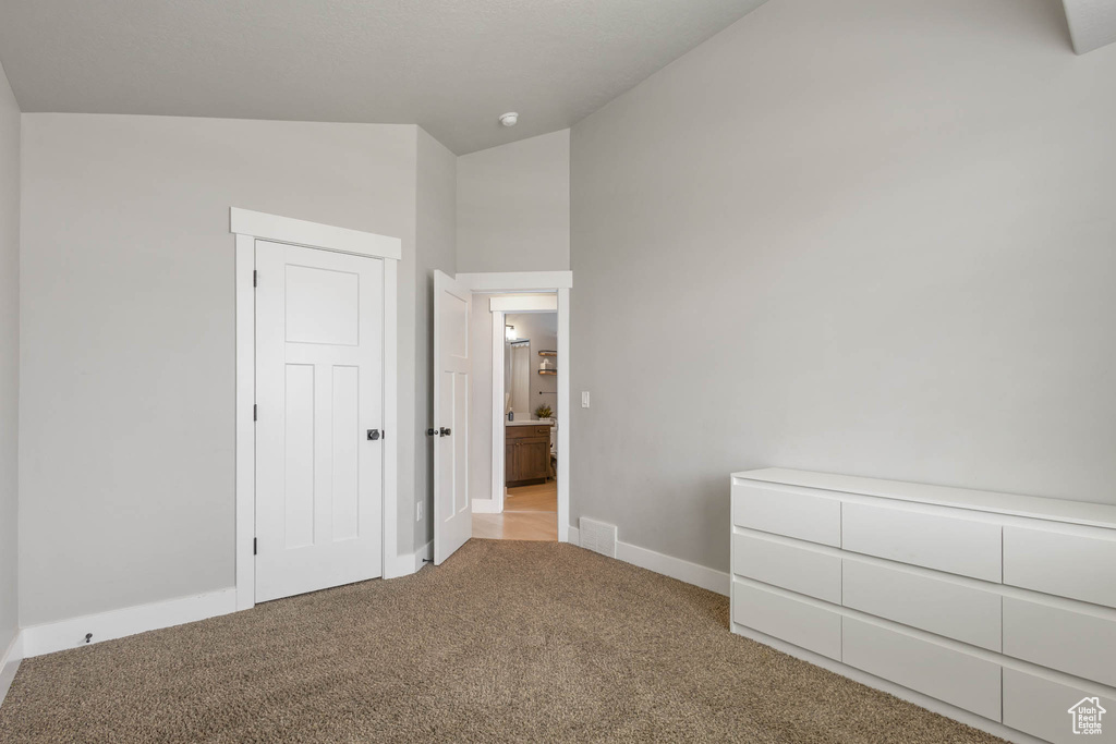 Unfurnished bedroom with vaulted ceiling, carpet flooring, and baseboards