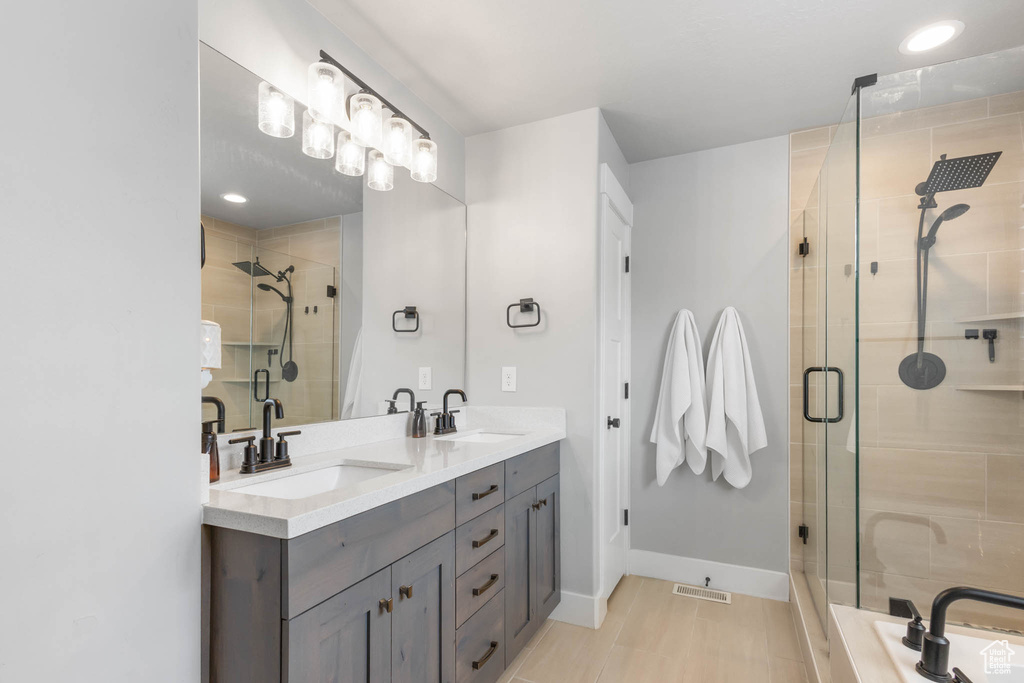 Bathroom featuring a stall shower, double vanity, and baseboards