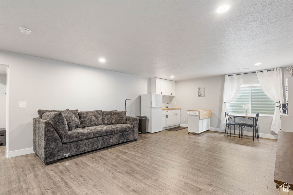 Living room with light wood-type flooring, recessed lighting, and baseboards