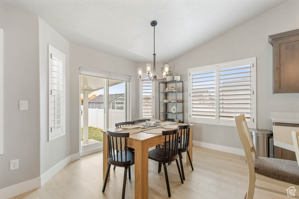 Dining room featuring a chandelier, baseboards, light wood finished floors, and vaulted ceiling