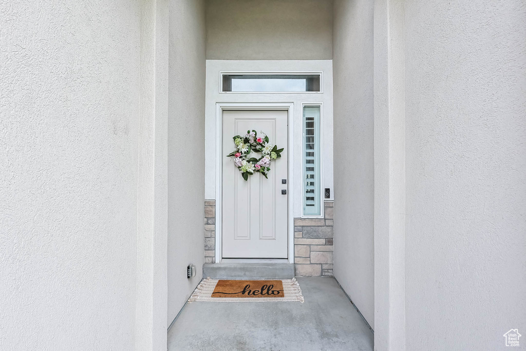 View of exterior entry with stucco siding and stone siding
