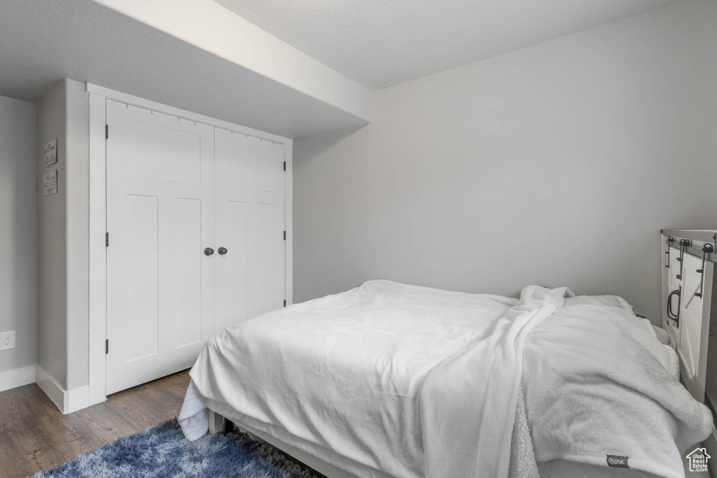 Bedroom featuring wood finished floors, baseboards, and a closet