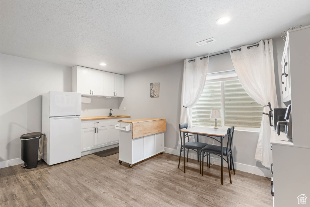Kitchen featuring freestanding refrigerator, wood counters, light wood-style floors, baseboards, and recessed lighting