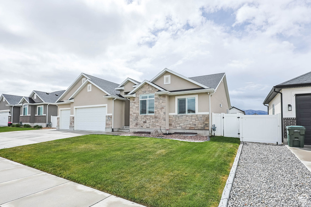 Craftsman house featuring stucco siding, stone siding, a gate, a garage, and driveway