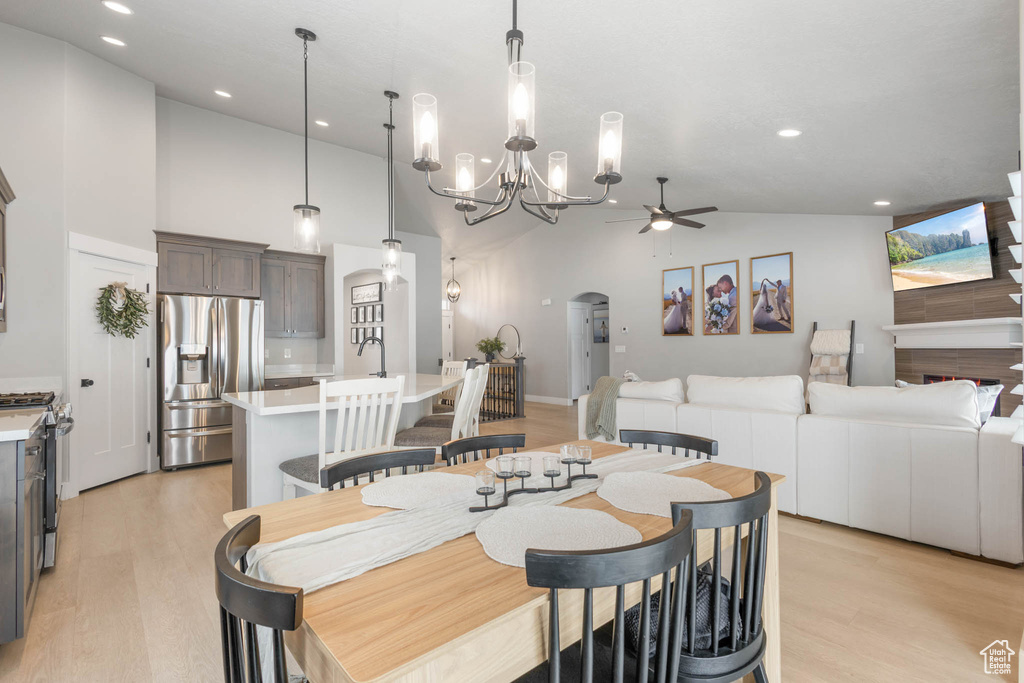 Dining room with a ceiling fan, light wood-style floors, arched walkways, recessed lighting, and a chandelier