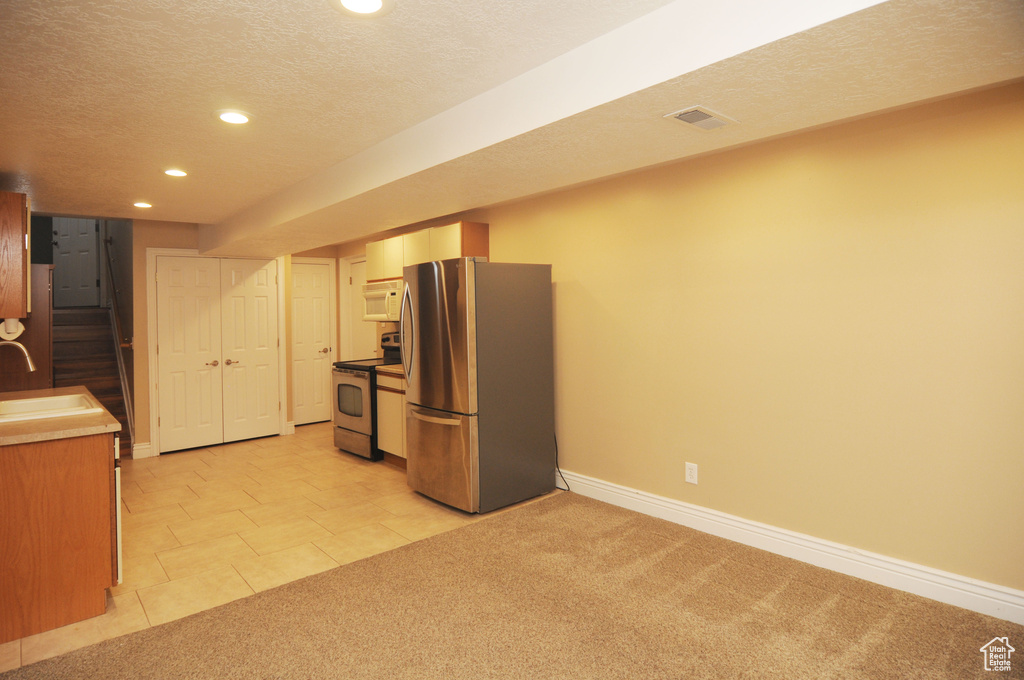 Kitchen with appliances with stainless steel finishes, recessed lighting, a sink, a textured ceiling, and baseboards