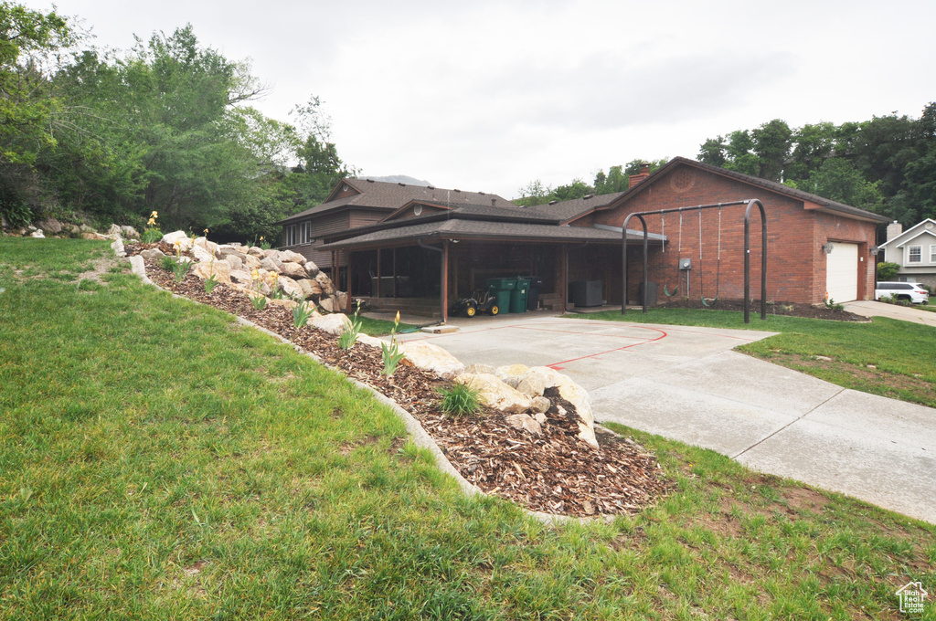 View of home's exterior with a yard, brick siding, a garage, driveway, and a chimney