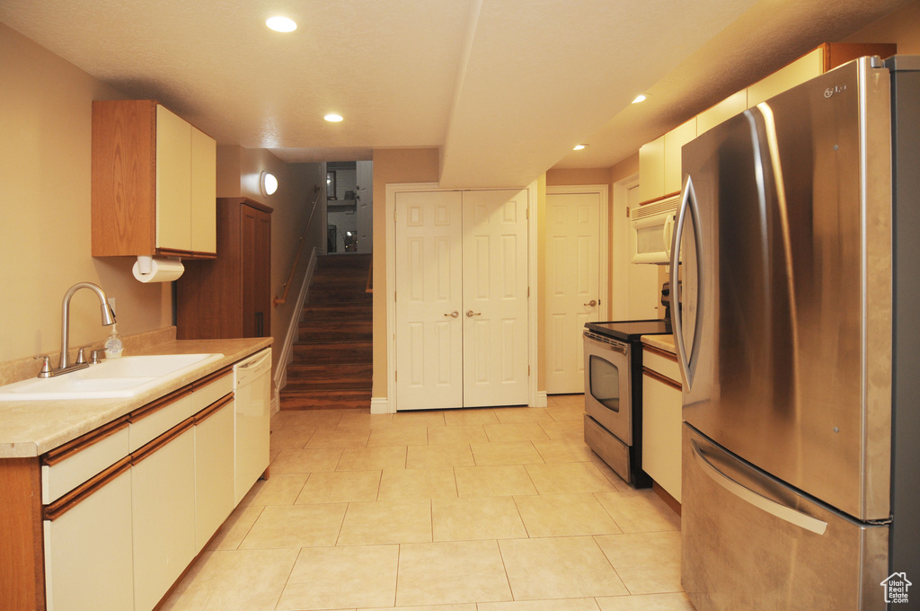 Kitchen featuring appliances with stainless steel finishes, a sink, recessed lighting, white cabinetry, and light countertops
