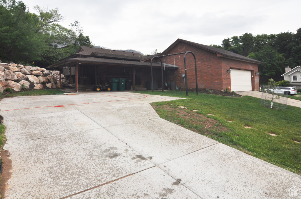 View of front of house featuring a front yard, driveway, a garage, and brick siding