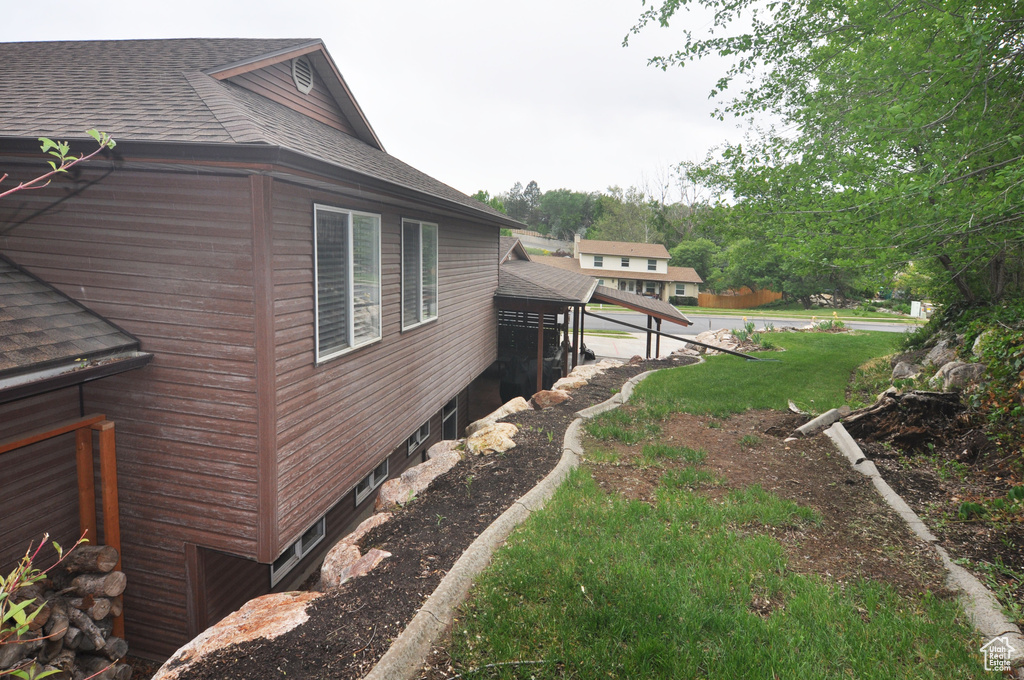 View of property exterior featuring a shingled roof and a lawn