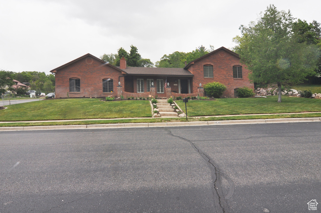 View of front of home featuring a chimney, a front lawn, and brick siding