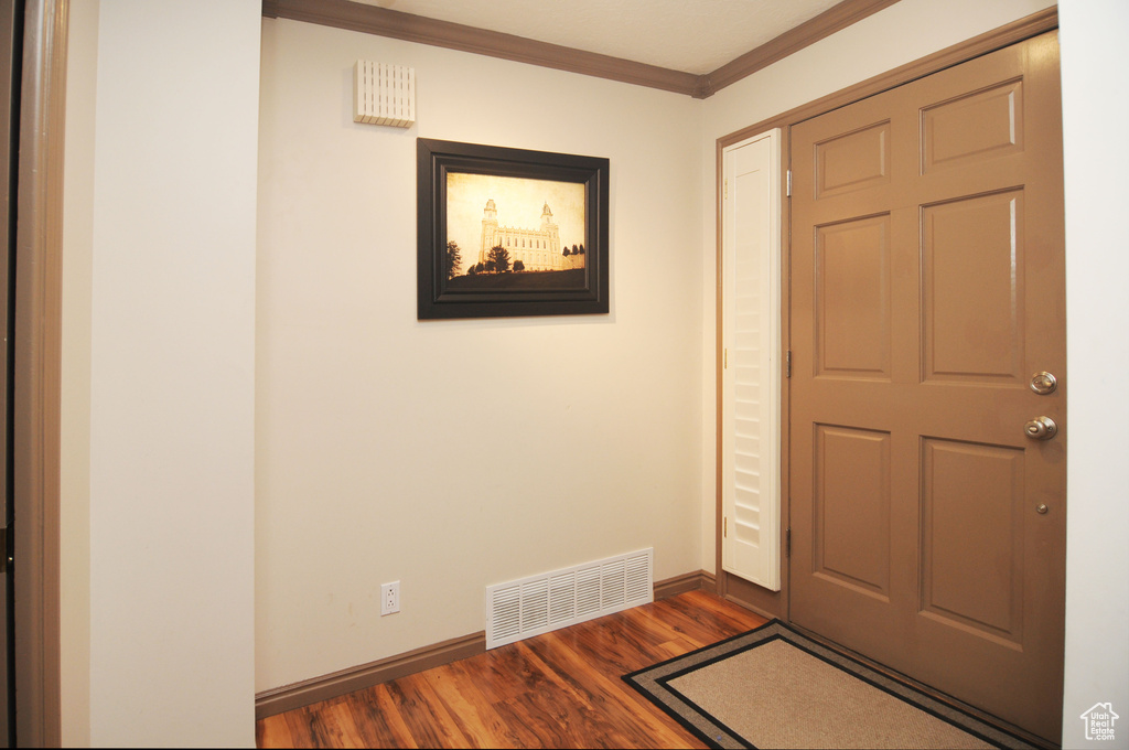 Foyer entrance with crown molding, dark wood finished floors, and baseboards