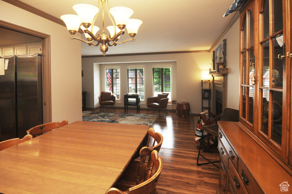 Dining space featuring dark wood finished floors, crown molding, and a chandelier