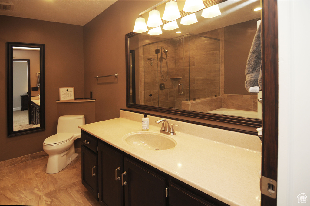 Full bath featuring a tile shower, toilet, baseboards, and vanity