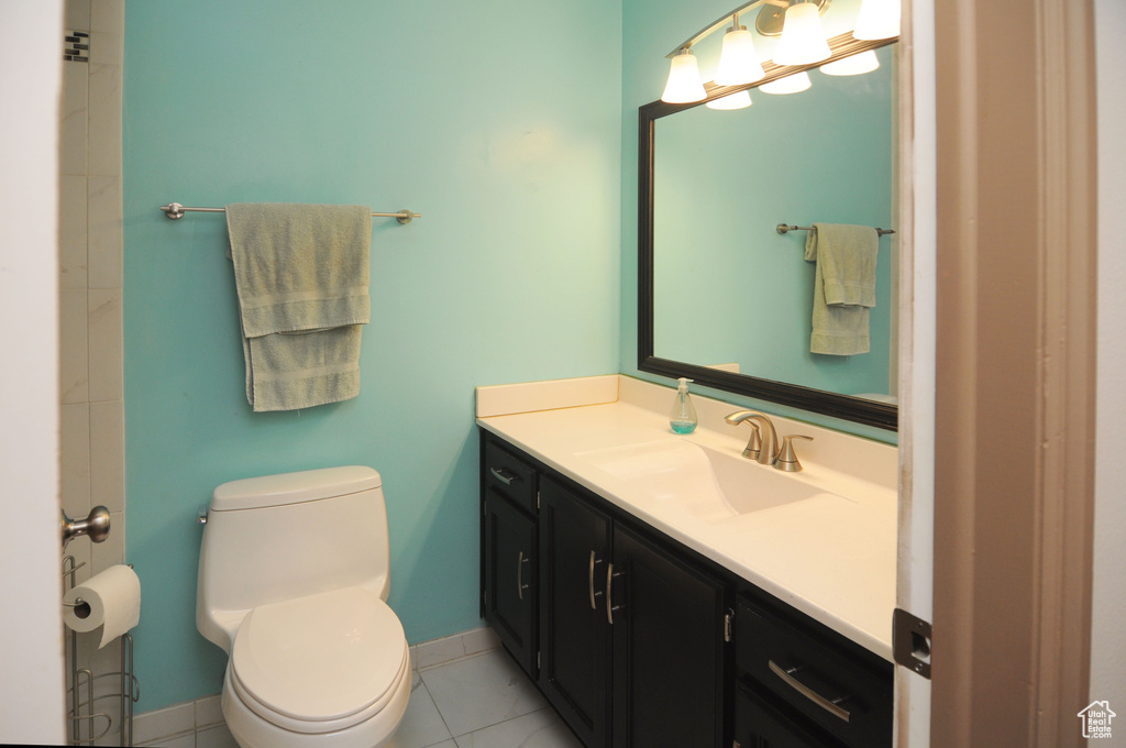 Bathroom featuring toilet, vanity, baseboards, and tile patterned flooring