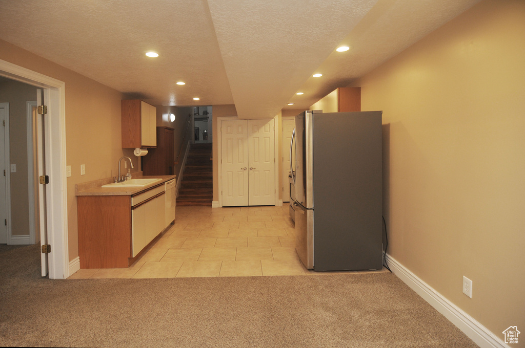 Kitchen featuring freestanding refrigerator, a sink, light colored carpet, recessed lighting, and light countertops