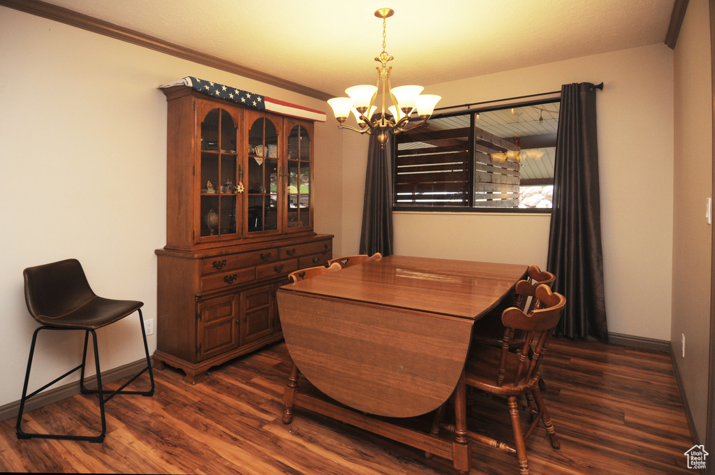 Dining space with a chandelier, dark wood finished floors, baseboards, and crown molding