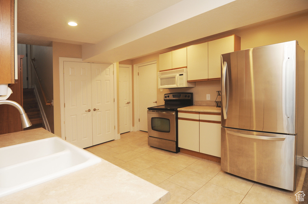 Kitchen with stainless steel appliances, a sink, light countertops, recessed lighting, and light tile patterned floors