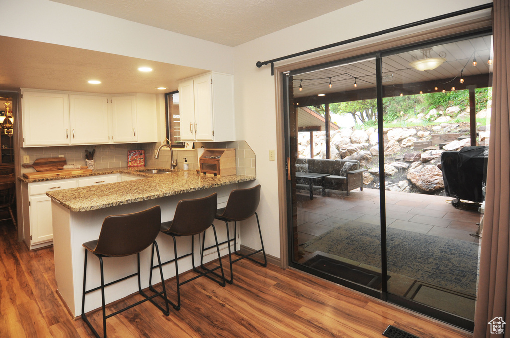 Kitchen with a sink, light stone counters, tasteful backsplash, white cabinets, and recessed lighting