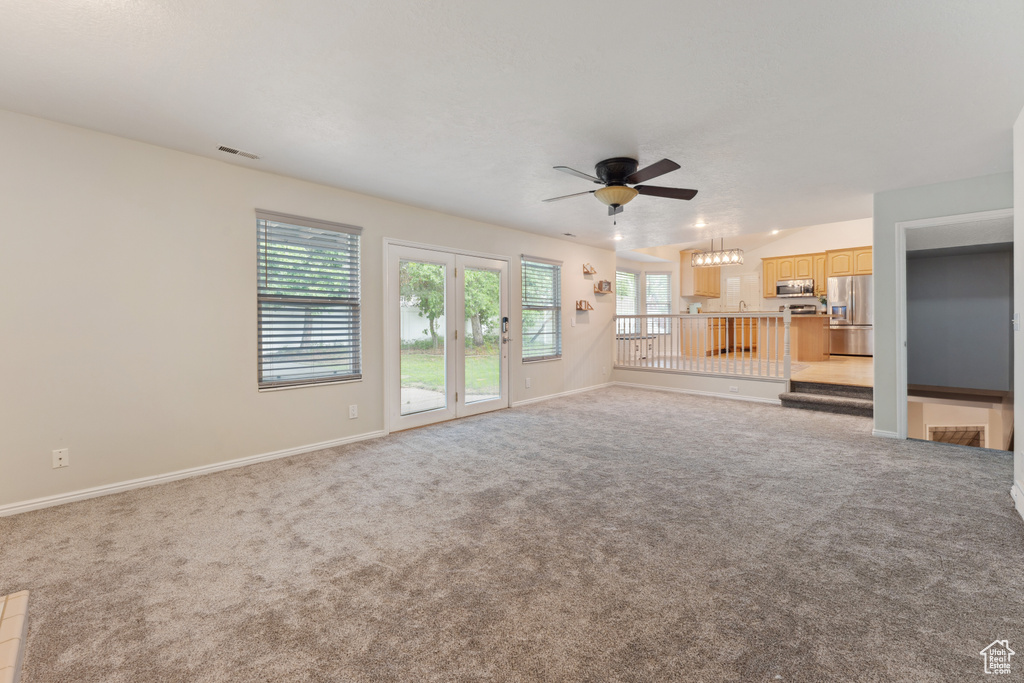 Unfurnished living room with a ceiling fan, carpet floors, and baseboards