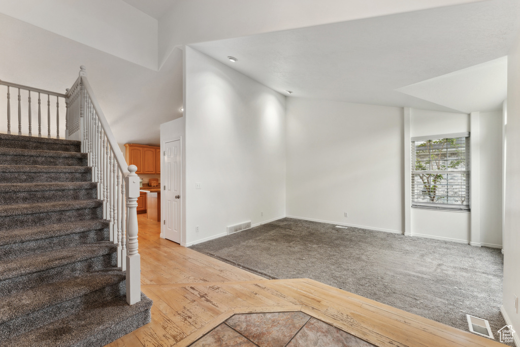 Staircase with baseboards, vaulted ceiling, wood finished floors, and carpet floors