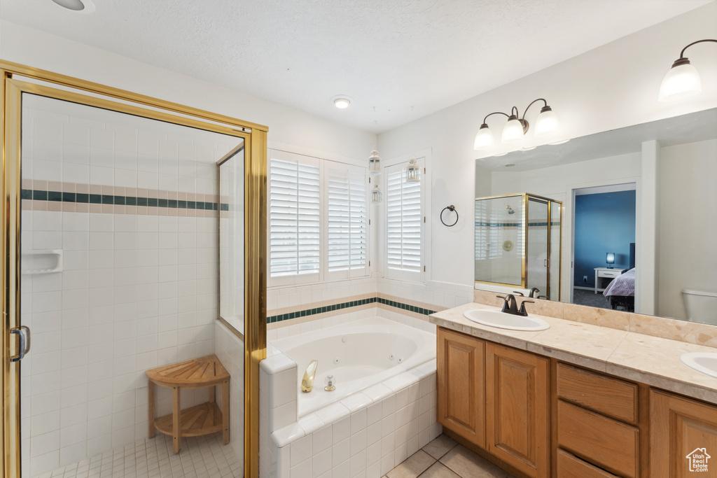 Ensuite bathroom featuring a jetted tub, tile patterned floors, a stall shower, and double vanity