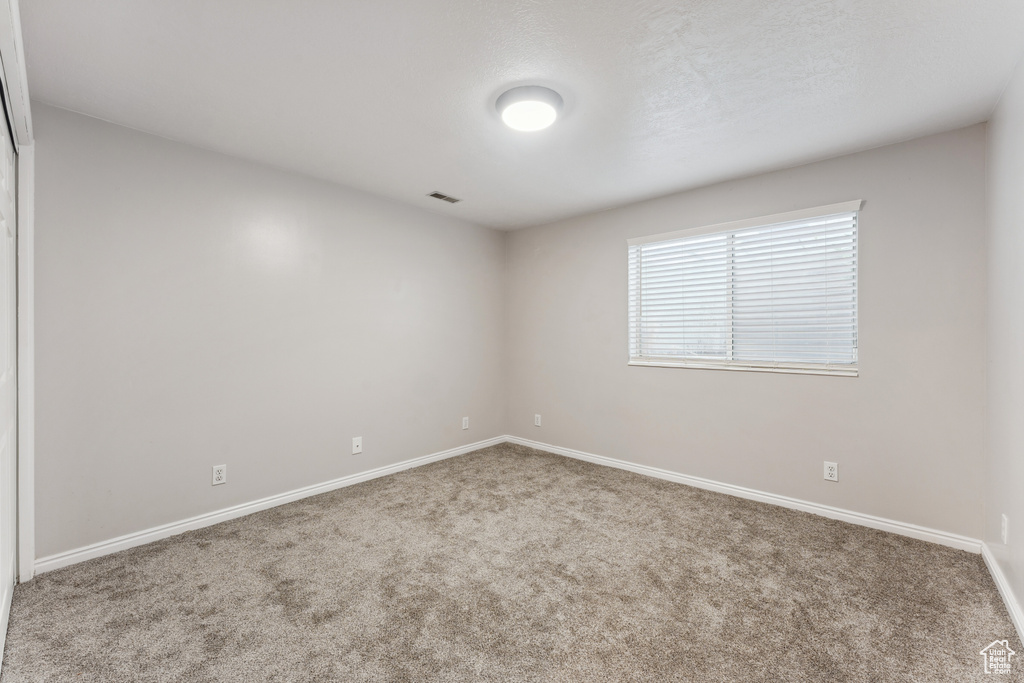 Carpeted spare room featuring baseboards