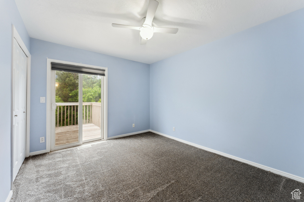 Carpeted spare room featuring a ceiling fan and baseboards