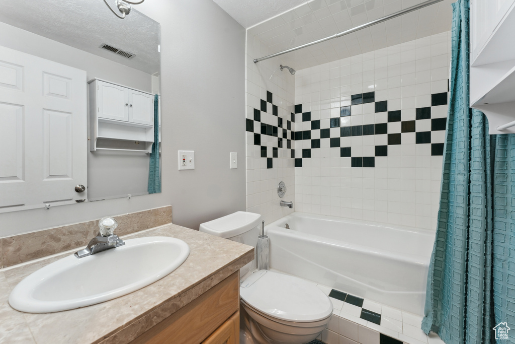 Bathroom with toilet, shower / bath combination with curtain, and vanity