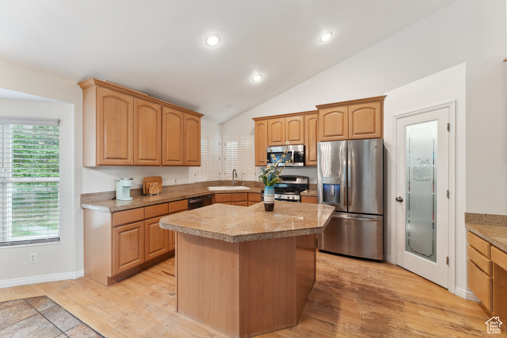 Kitchen with stainless steel appliances, a sink, light wood finished floors, recessed lighting, and lofted ceiling