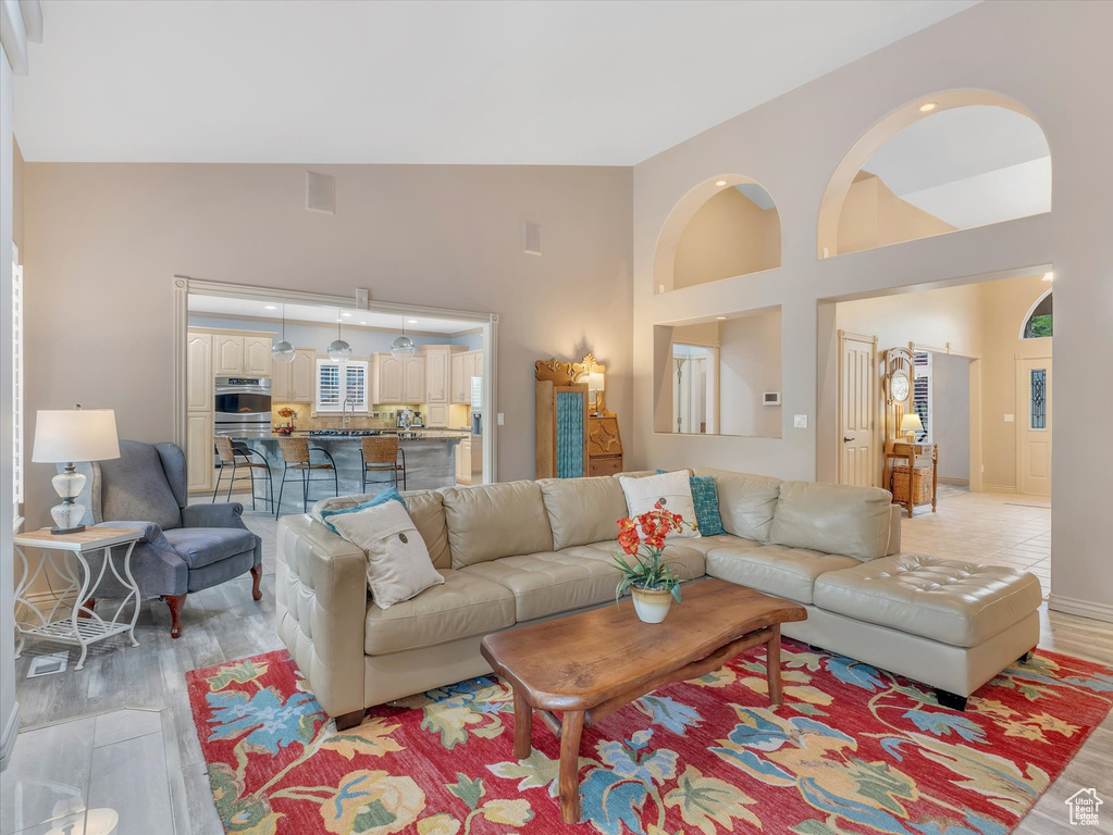 Living room featuring light wood-type flooring, high vaulted ceiling, and recessed lighting