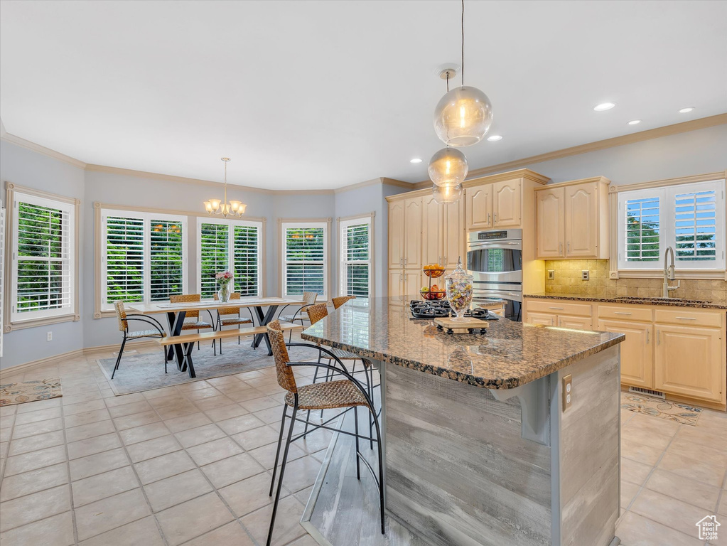 Kitchen featuring a sink, double oven, tasteful backsplash, stone counters, and a kitchen breakfast bar